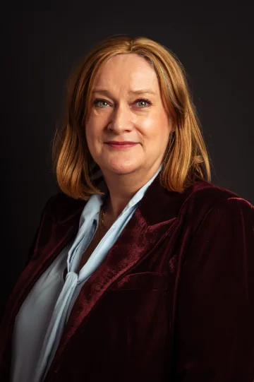 Portrait of Maud Bökkerink, smiling, in a dark red velvet jacket